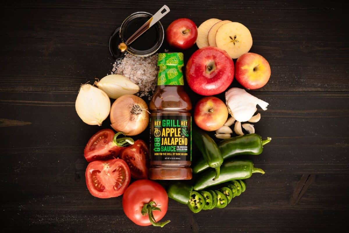 Bottle of sauce on countertop surrounded by raw ingredients.