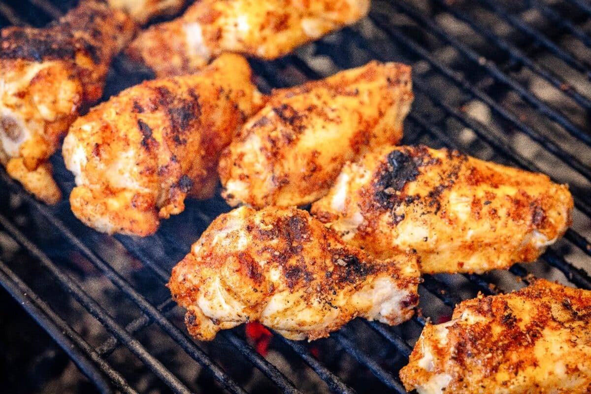 Wings cooking on grill grates.