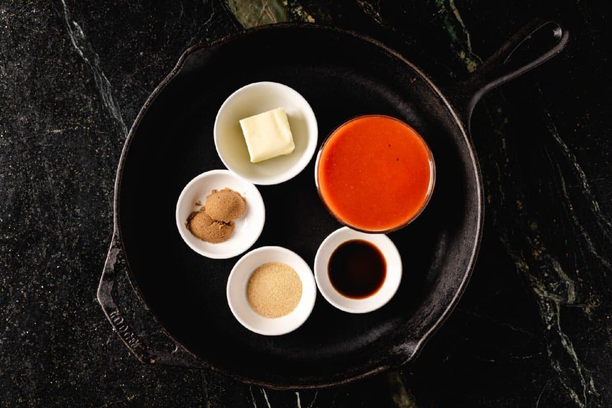 Sauce ingredients in glass bowls inside a cast iron skillet.