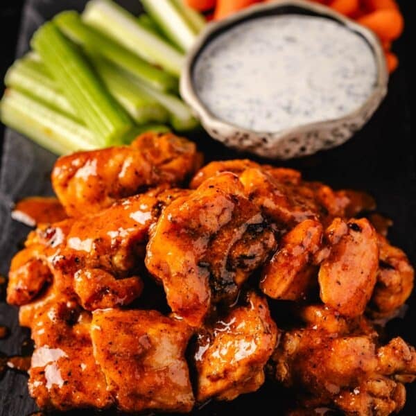 Grilled buffalo chicken bites next to carrot and celery sticks, and a bowl of ranch.