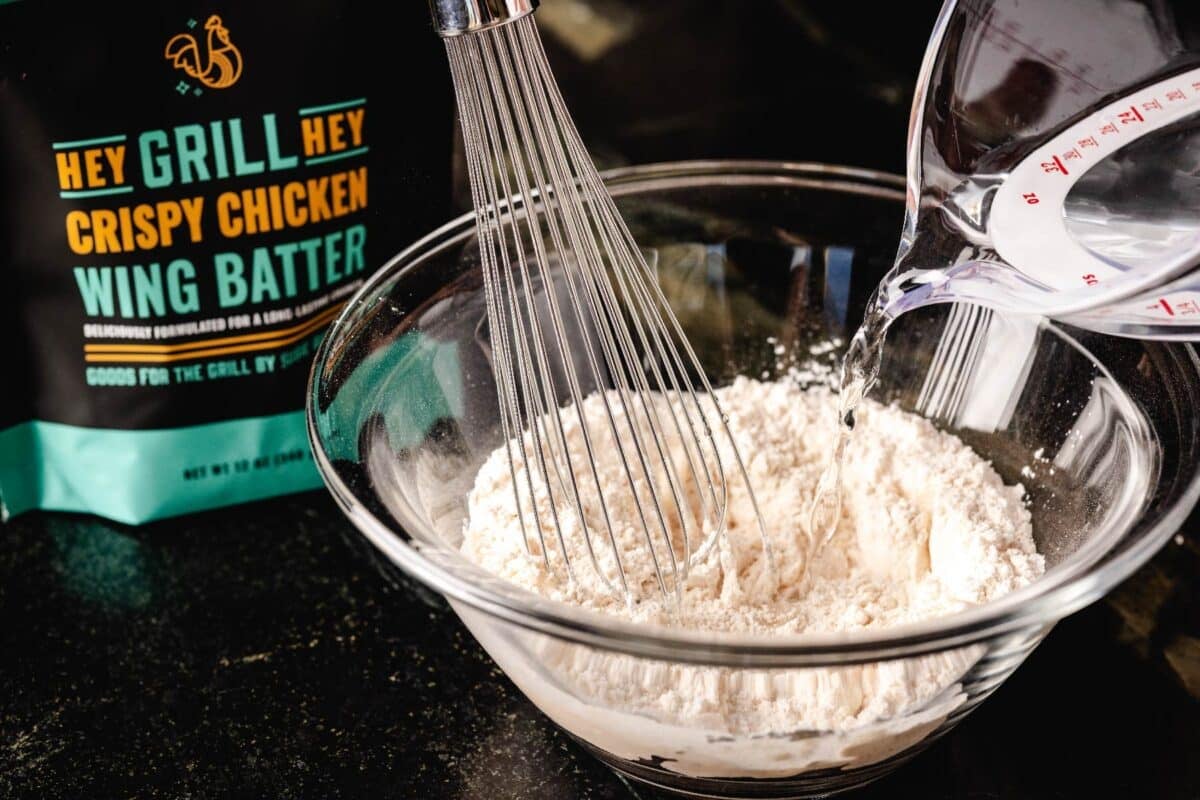 Batter in a glass bowl being whisked, next to a bag of the batter.