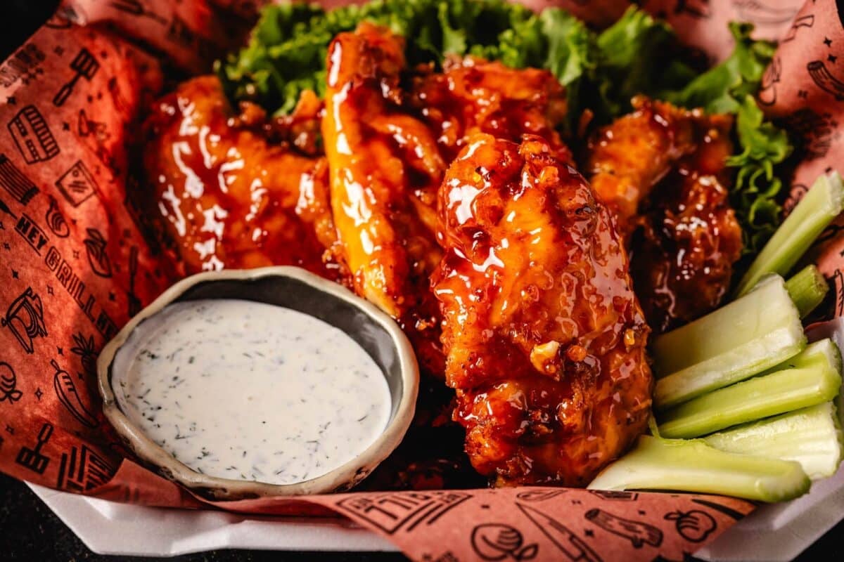 Glazed chicken tenders in basket with bowl of ranch.