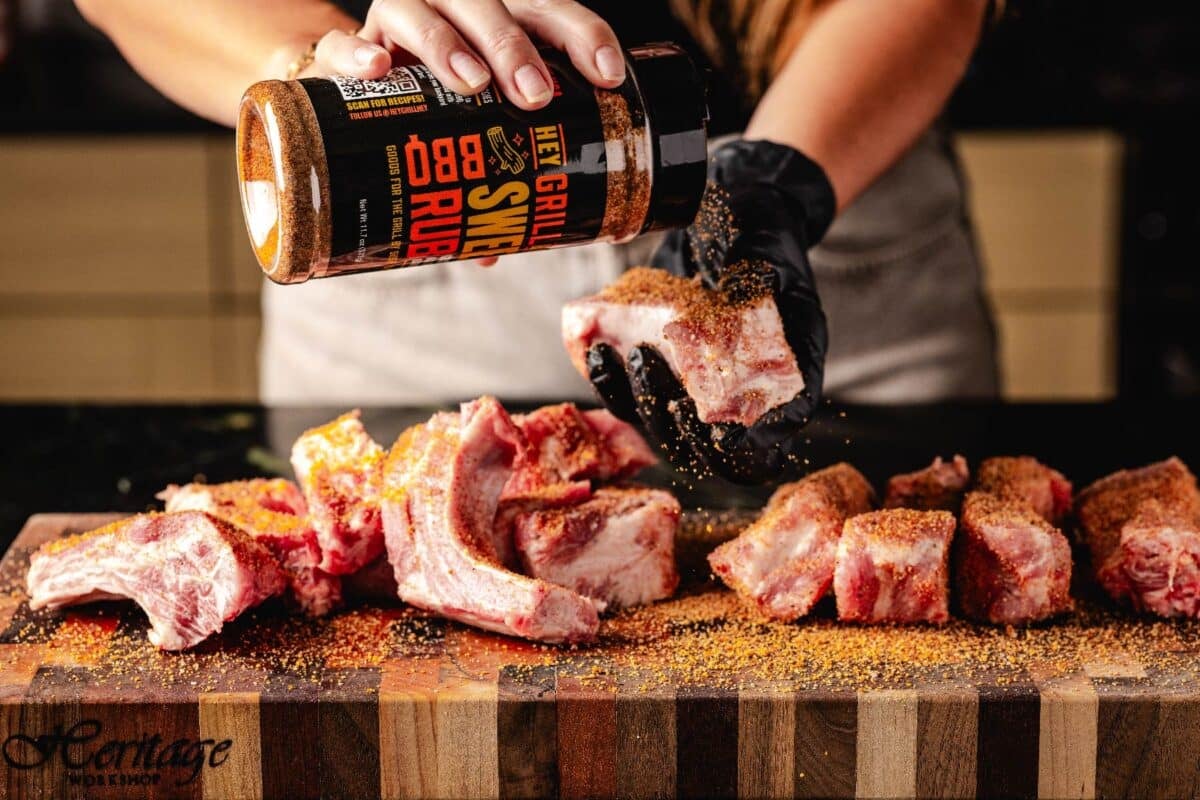 Sliced ribs on cutting board being seasoned with Sweet Rub.