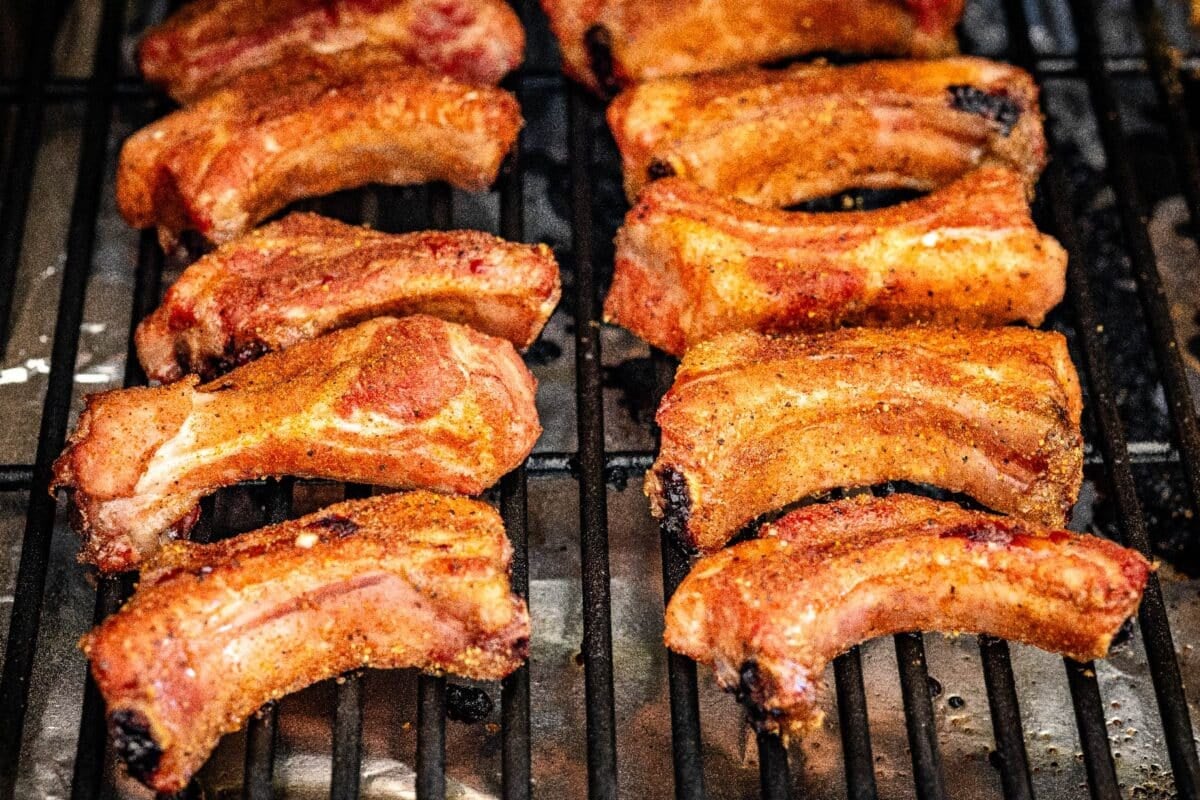 Ribs being smoked on grill grates.