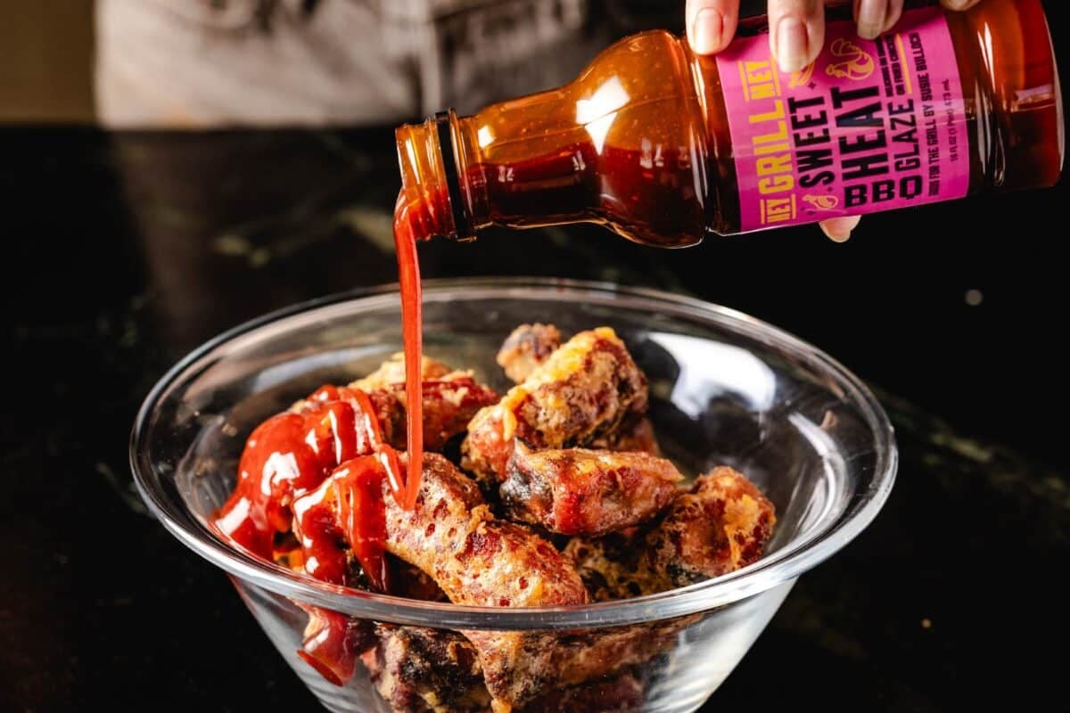 Ribs in bowl being drizzled with Sweet Heat Glaze.