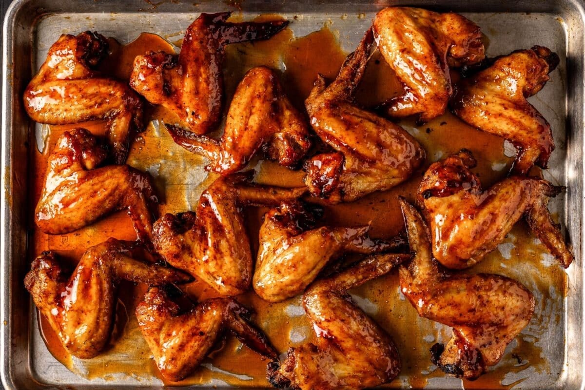 Wings on baking sheet drizzled with glaze.