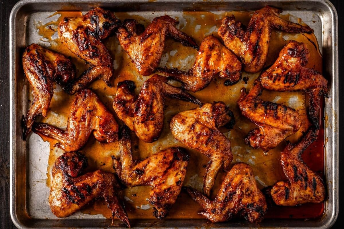 Smoked chicken wings on baking sheet drizzled with glaze.