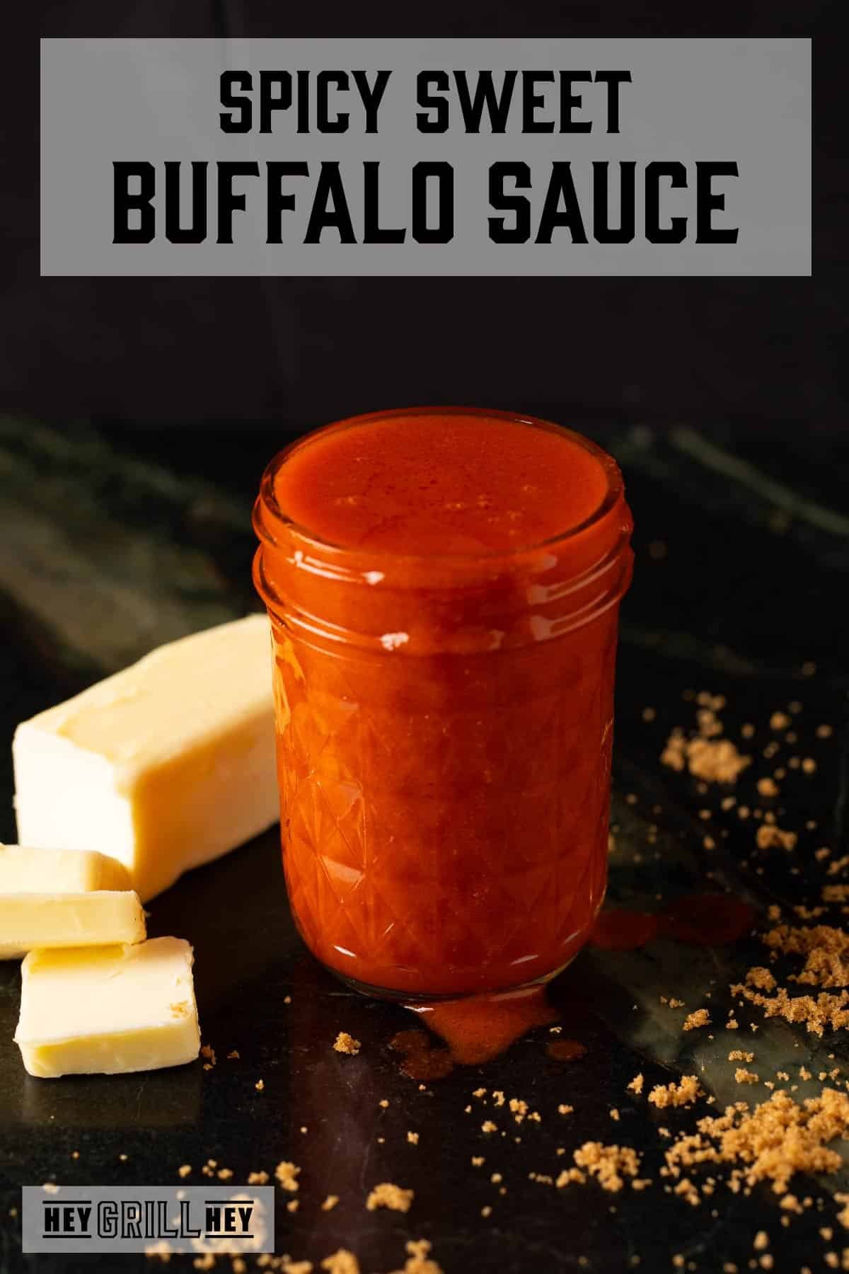 A clear mason jar with buffalo sauce, next to a stick of partially sliced butter. Text reads "Spicy Sweet Buffalo Sauce."