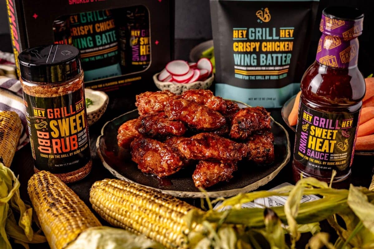 Glazed wings next to dipping sauces and containers of wing kit ingredients.