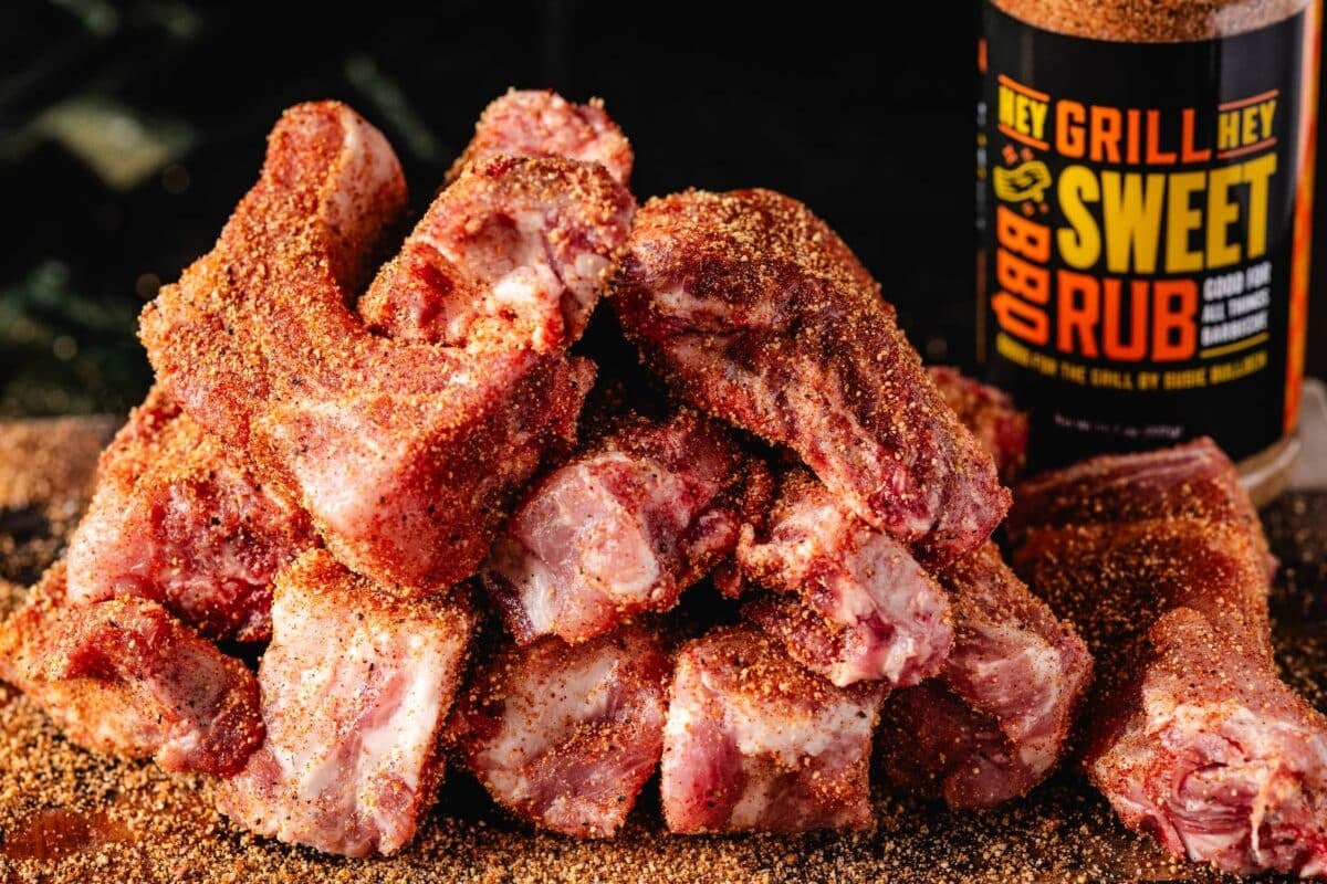 A pile of ribs in front of a jar of Sweet Rub.