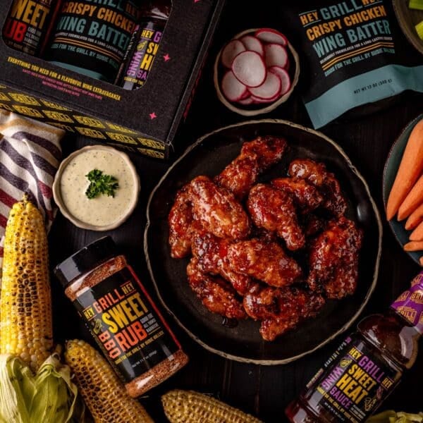 Glazed wings next to dipping sauces and containers of wing kit ingredients.