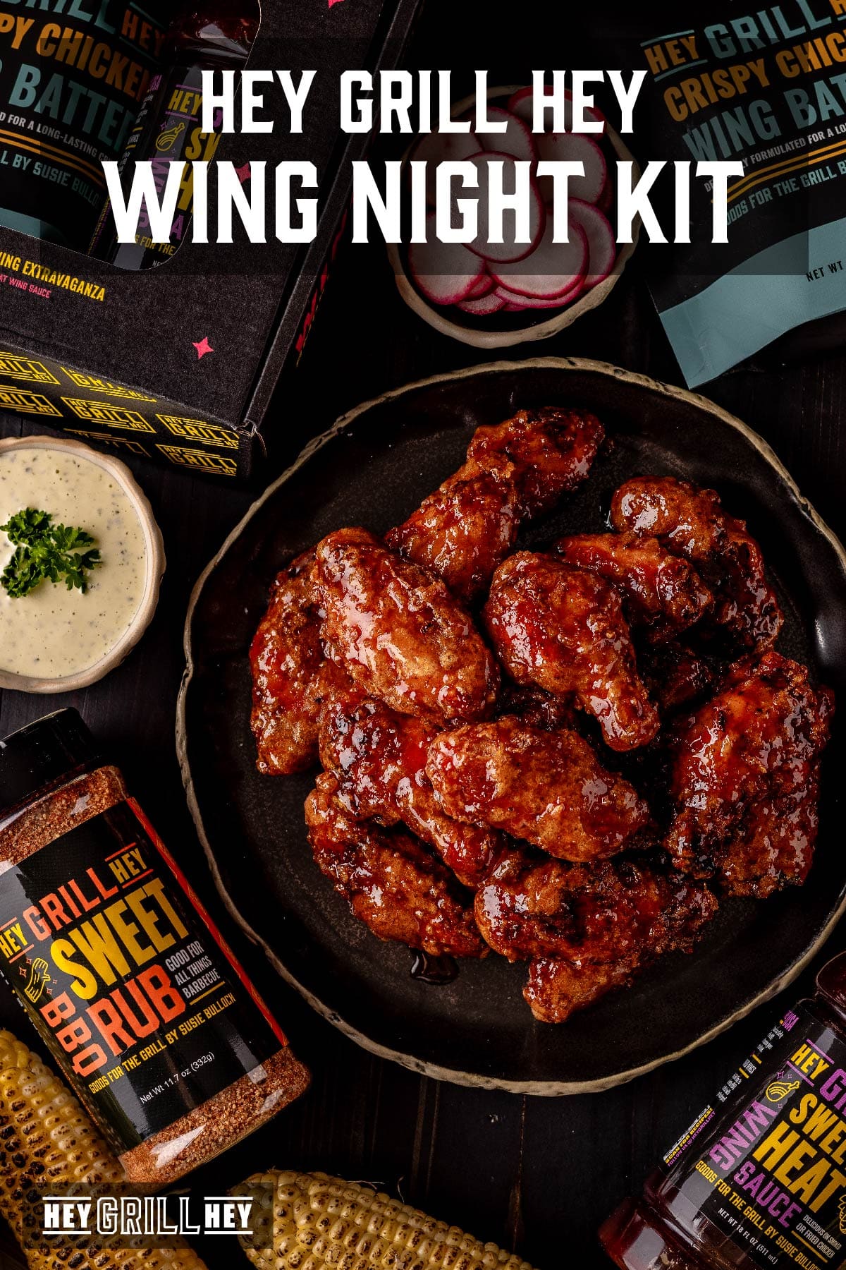 Glazed wings next to dipping sauces and containers of wing kit ingredients. Text reads "Hey Grill Hey Wing Night Kit."