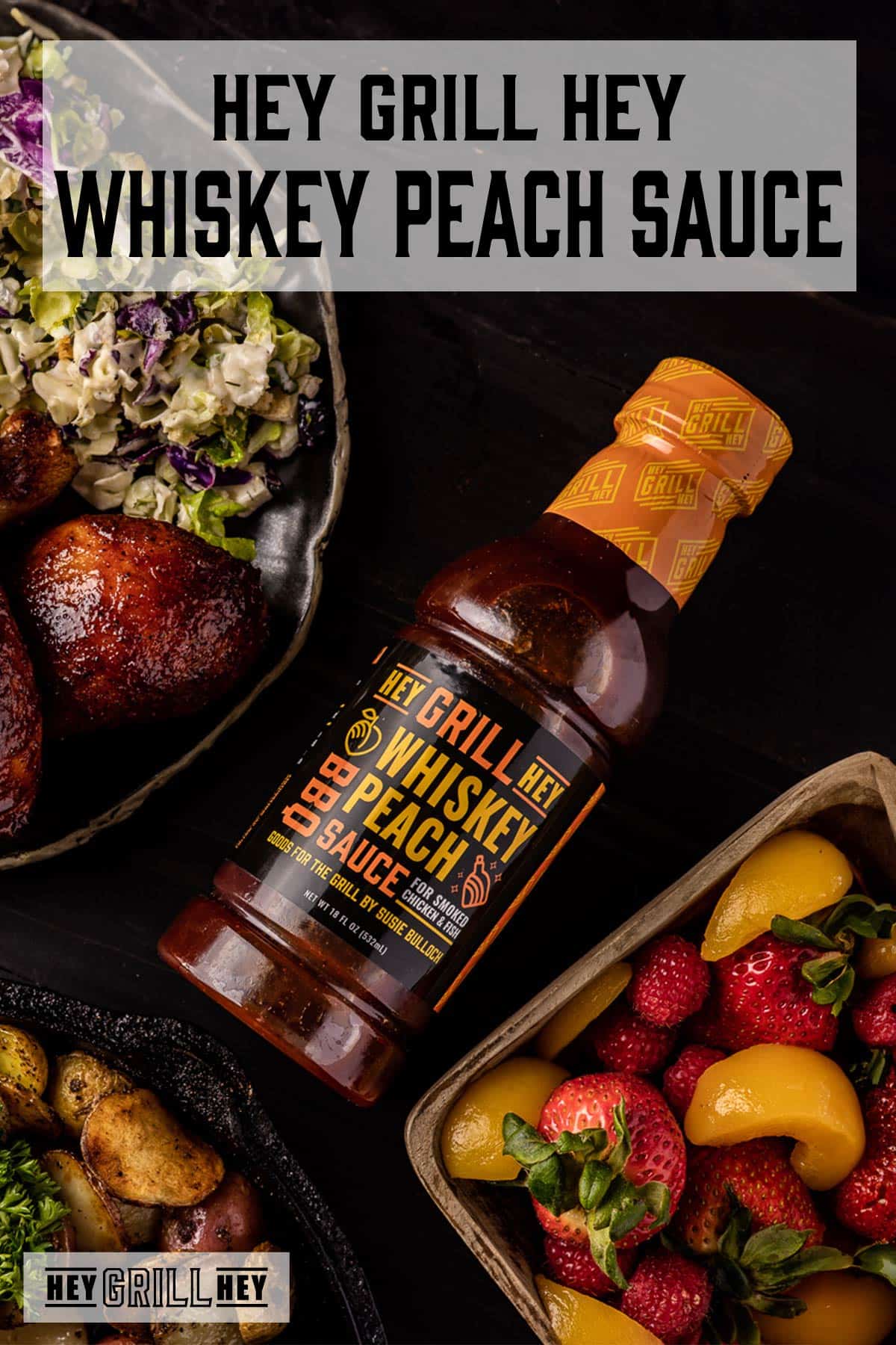 A bottle of BBQ sauce next to a bowl of chicken and coleslaw, and a dish or fruit. Text reads "Hey Grill Hey Whiskey Peach BBQ Sauce."