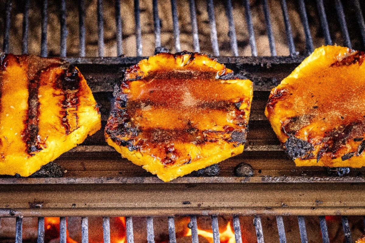 Pineapple slices on grill grates with grill marks.