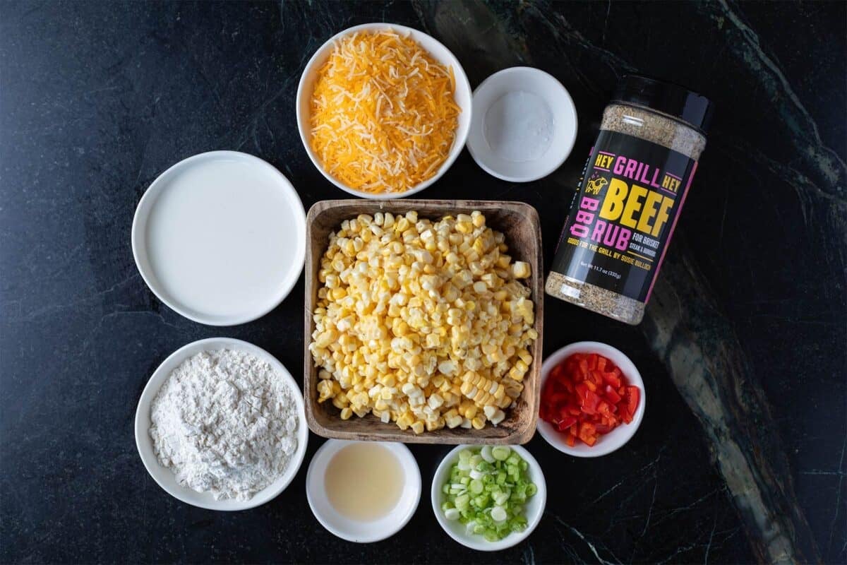 Corn fritter ingredients in individual bowls on a countertop.