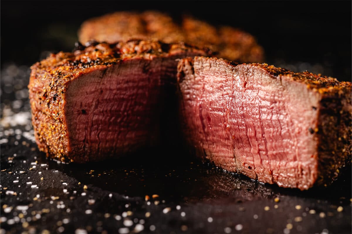 A perfectly medium rare filet mignon sliced open atop a black serving board.