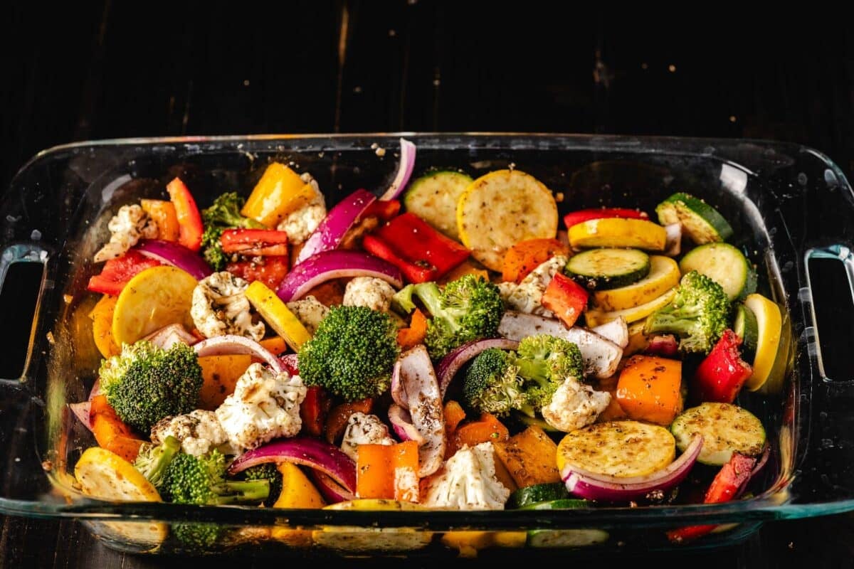 Various sliced veggies in a clear casserole dish.