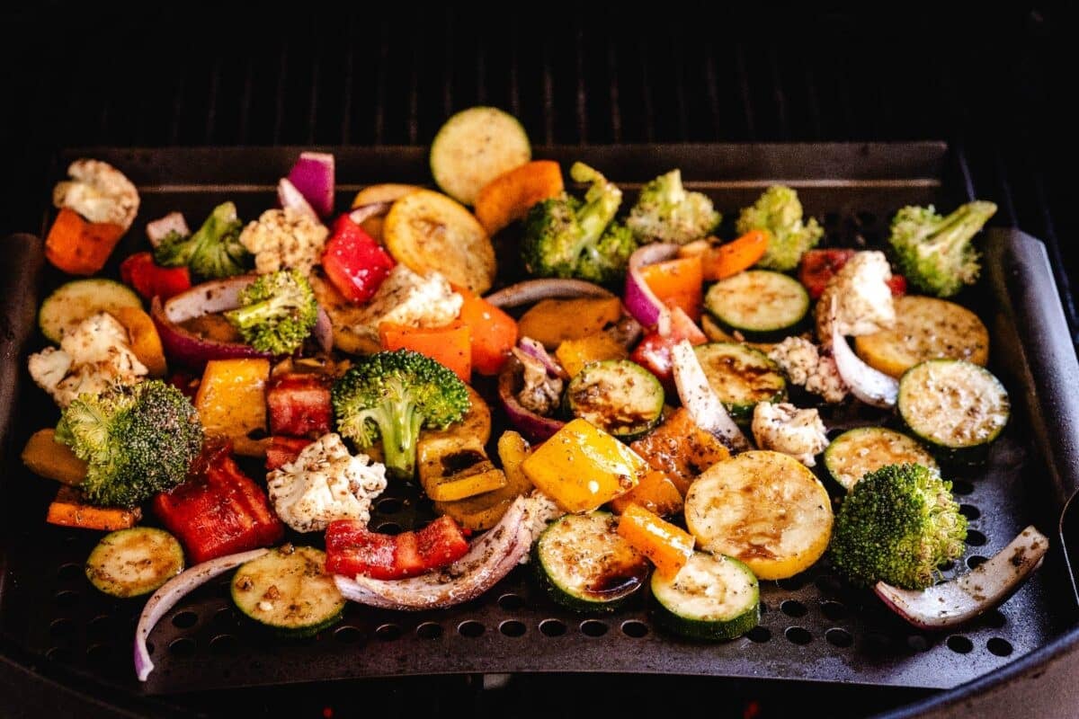 Various sliced vegetables in a grill basket.