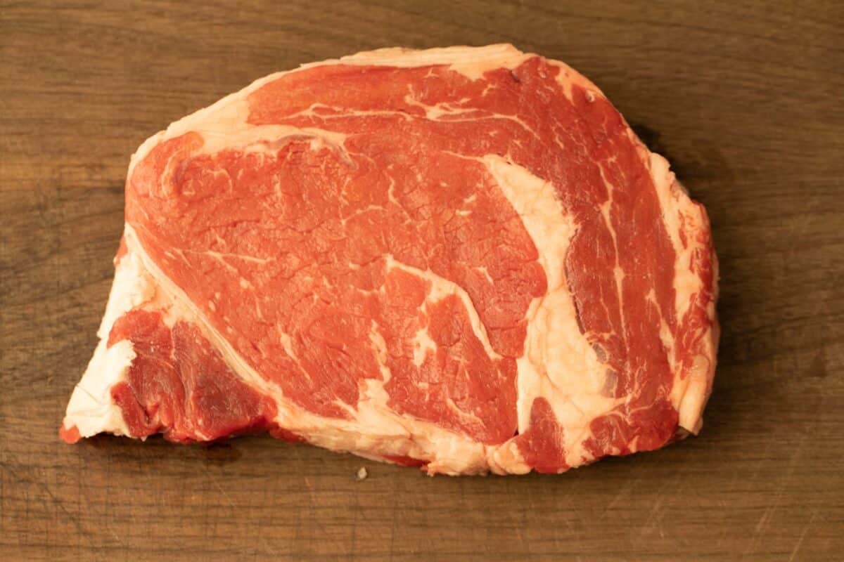 A raw prime steak on a cutting board.