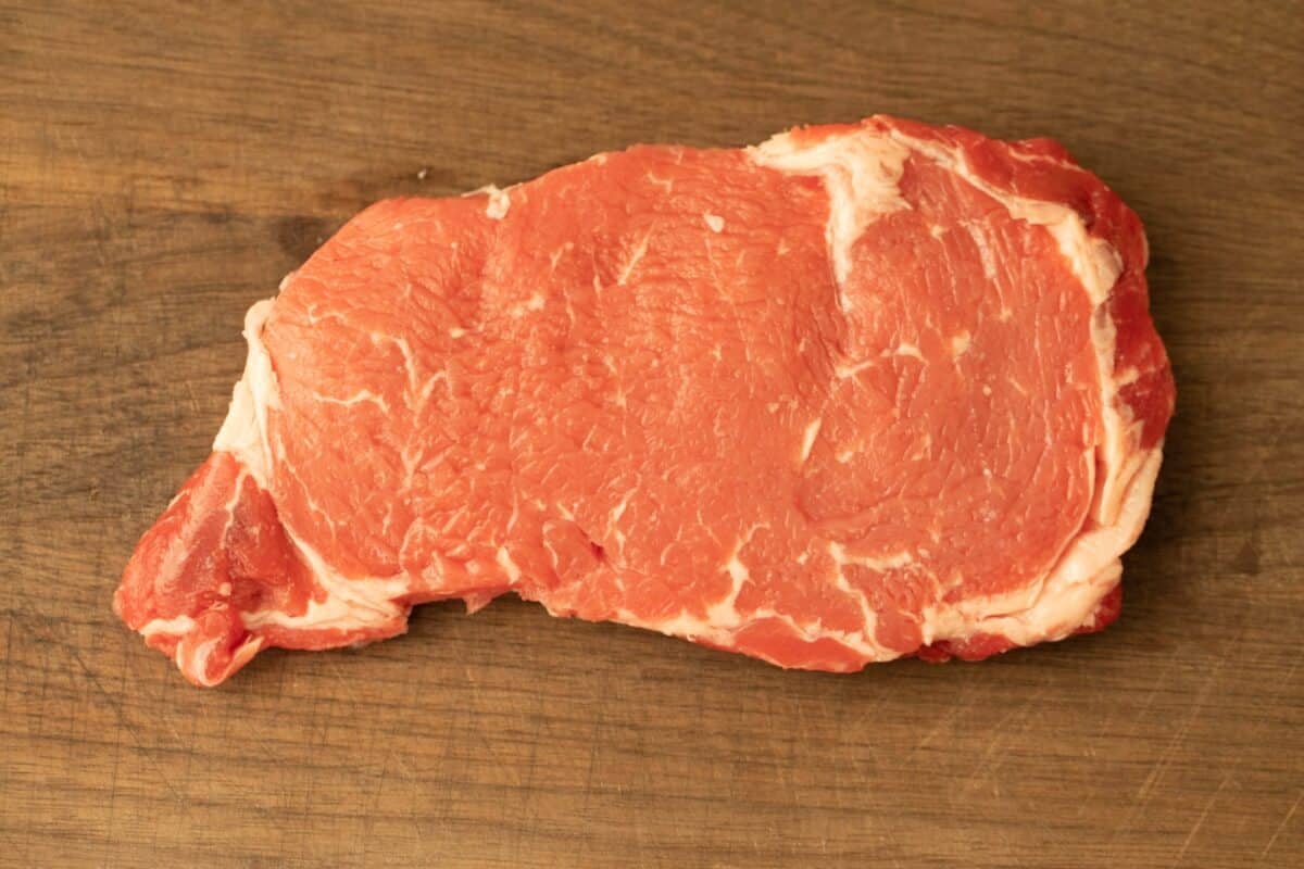 A raw select grade steak on a cutting board.