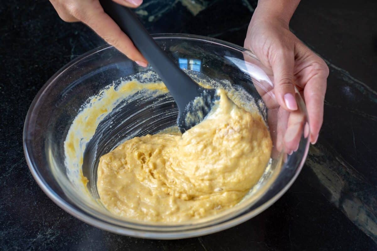 Batter in a glass bowl being mixed with a spatula.