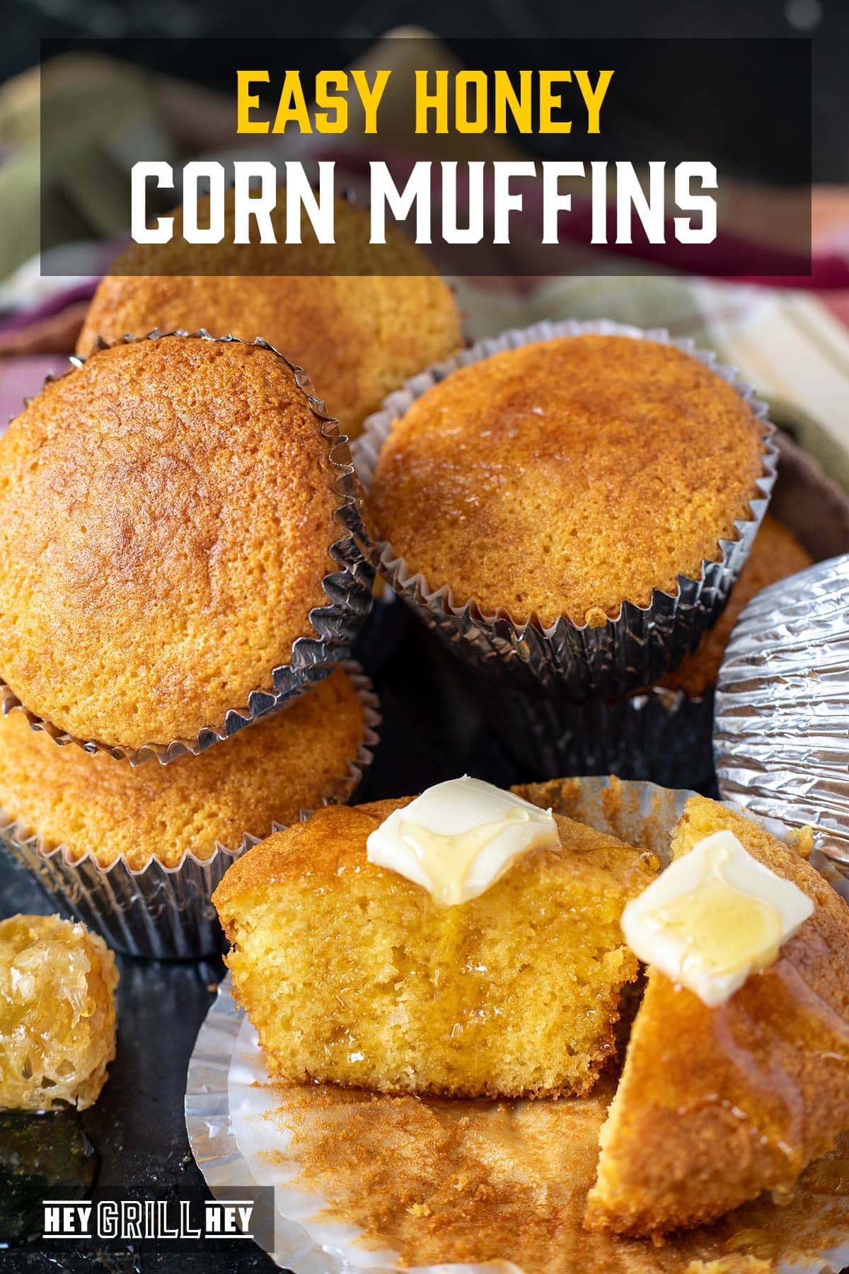 Cornbread muffins topped with butter and honey, piled on a countertop. The text overlay reads "Easy Honey Corn Muffins."