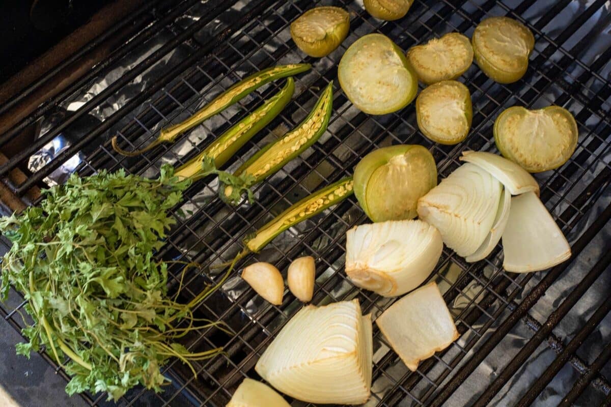 Cilantro, chopped onions, sliced peppers, and garlic on smoker grates.