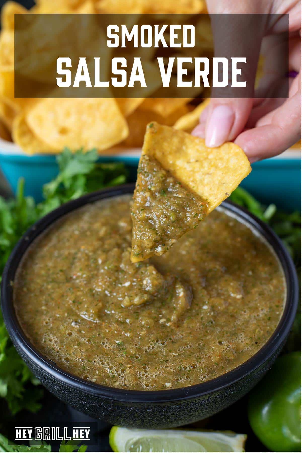 A black bowl with green chile salsa, and a tortilla chip dipping in it. The text overlay reads "Smoked Salsa Verde."