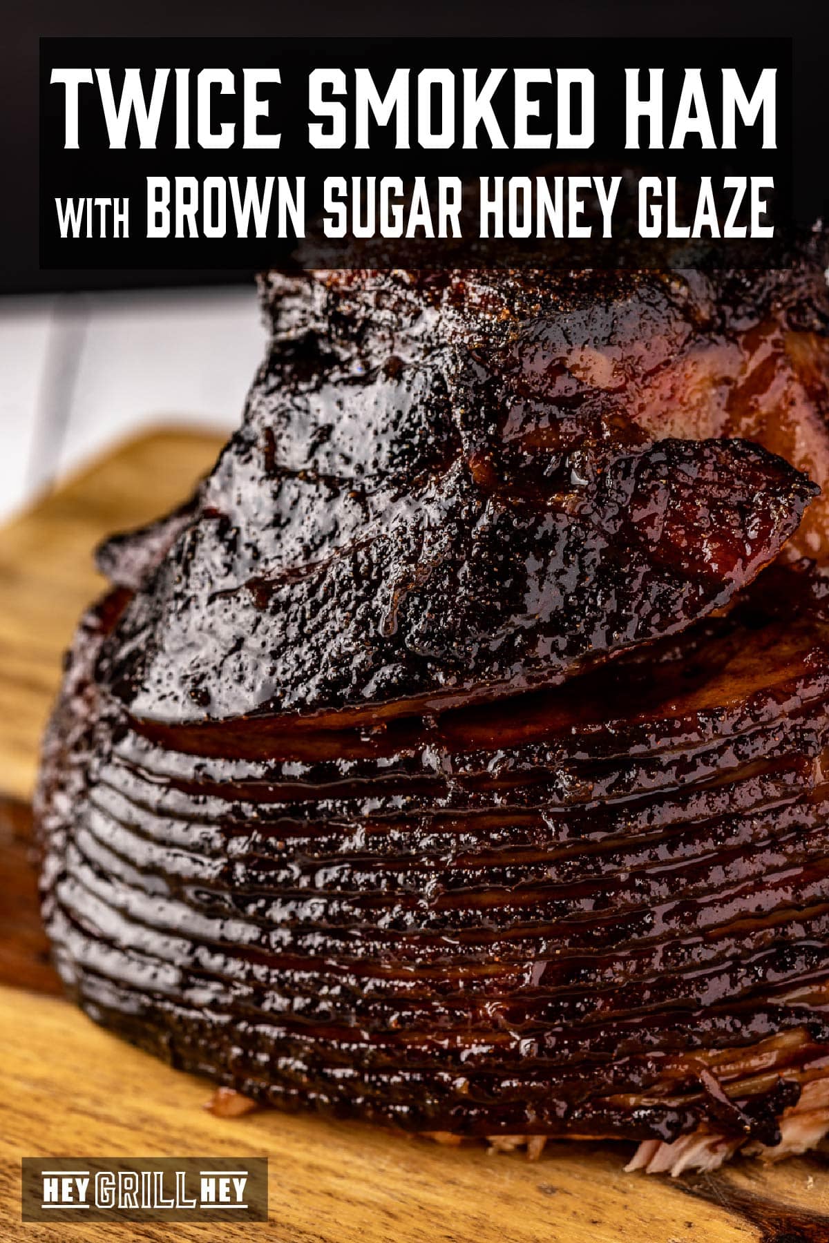 A spiral-cut ham on a cutting board being drizzled with glaze. The text overlay and the top reads "Twice Smoked Ham with Brown Sugar Honey Glaze," and the small one at the bottom reads "Hey Grill Hey."