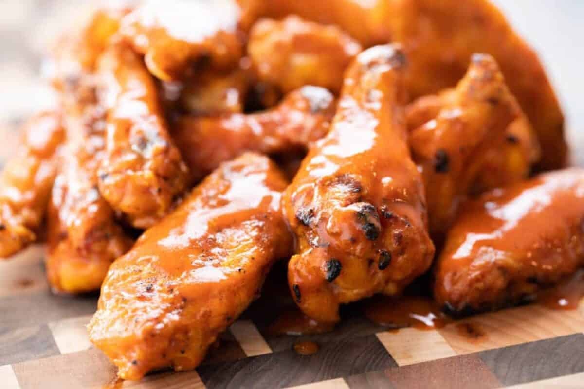 A chicken wing pile on a wooden platter.