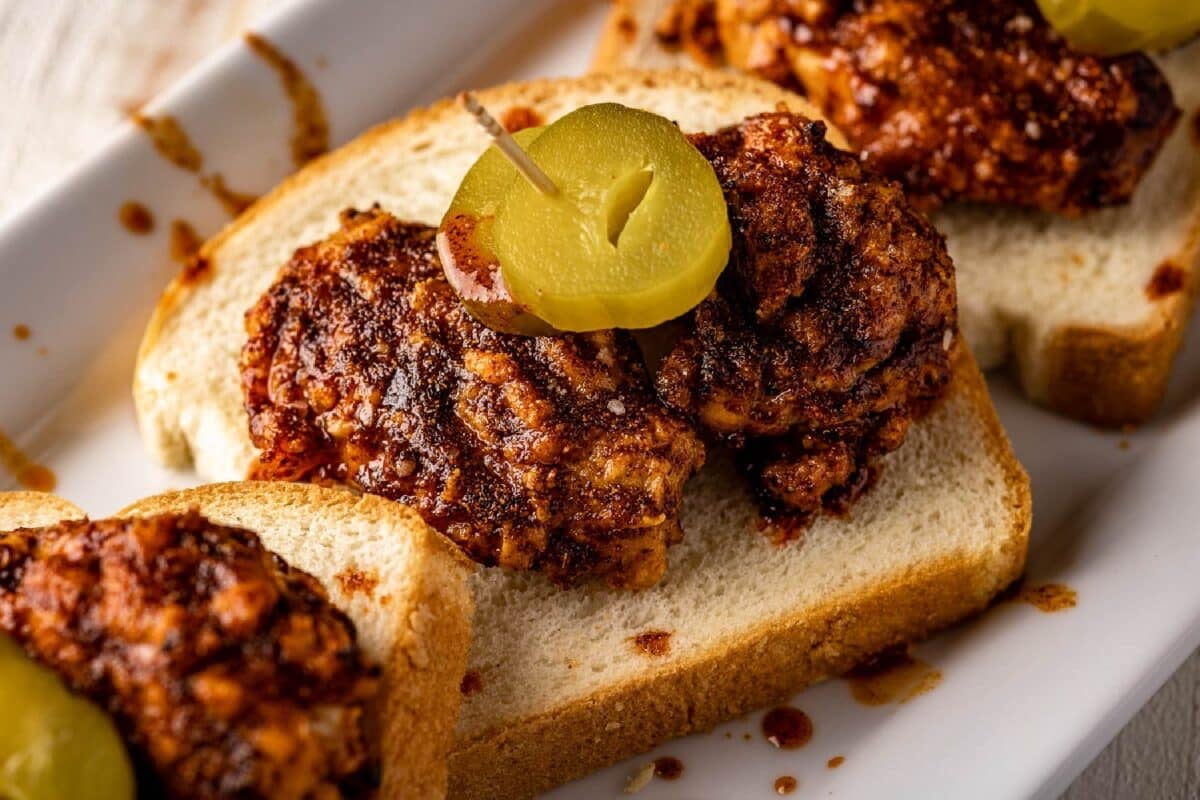 Nashville chicken wing sandwiches on bread with sliced pickles.