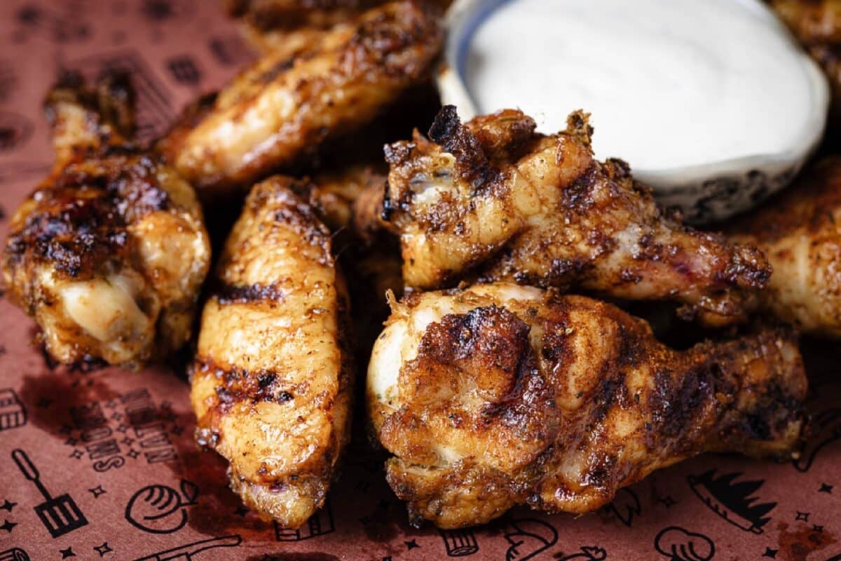 Jerk chicken wings and a cup of ranch on butcher paper.