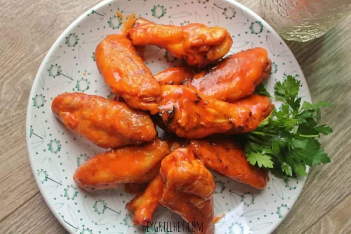 A Buffalo chicken wing dish on a white plate with garnish.