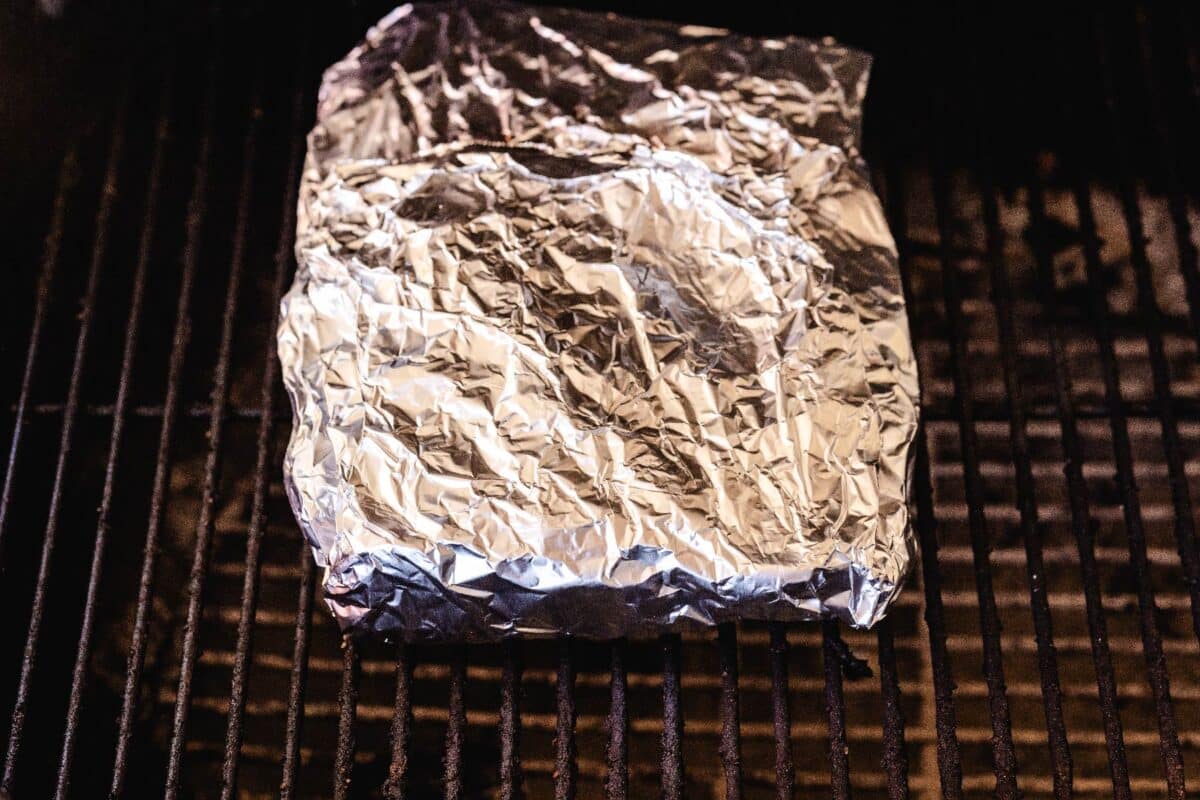 A foil packet sitting on a wire rack in the smoker.