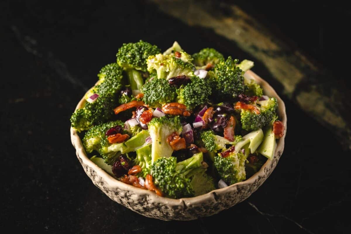 A bowl of broccoli salad on a black countertop.