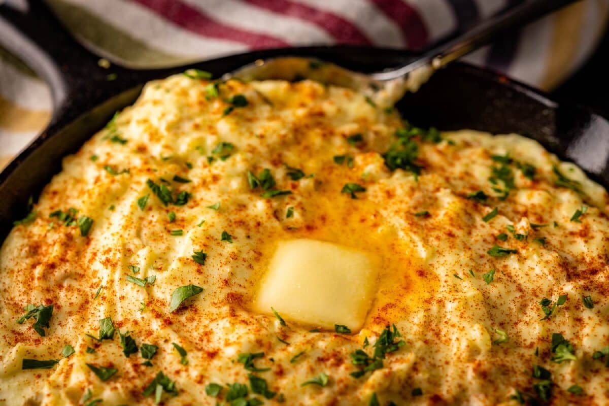 A skillet of mashed potatoes with a pad of butter melting on top.