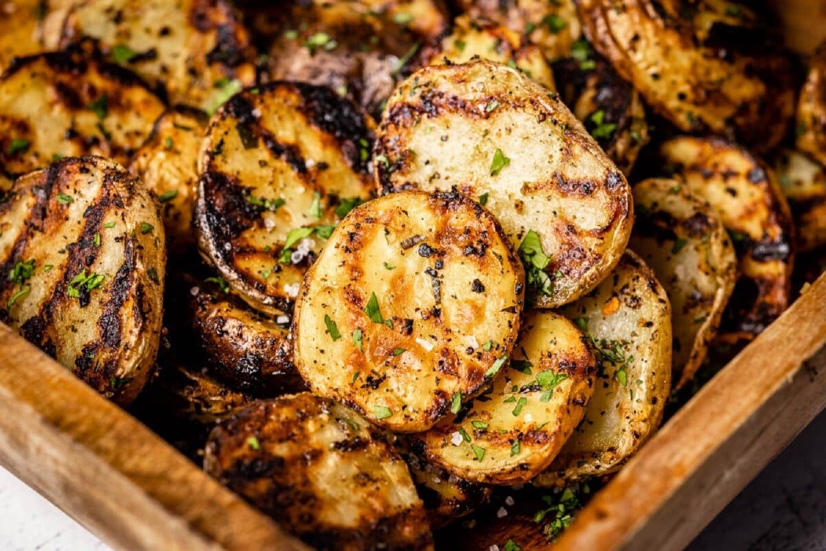 BBQ grilled potato slices inside a wooden serving tray.