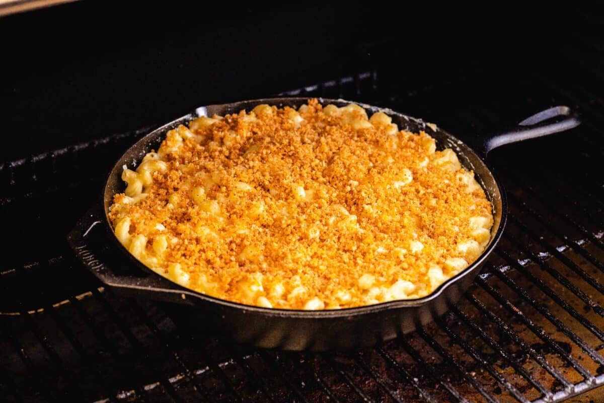 A skillet full of mac and cheese sitting on BBQ smoker grates.