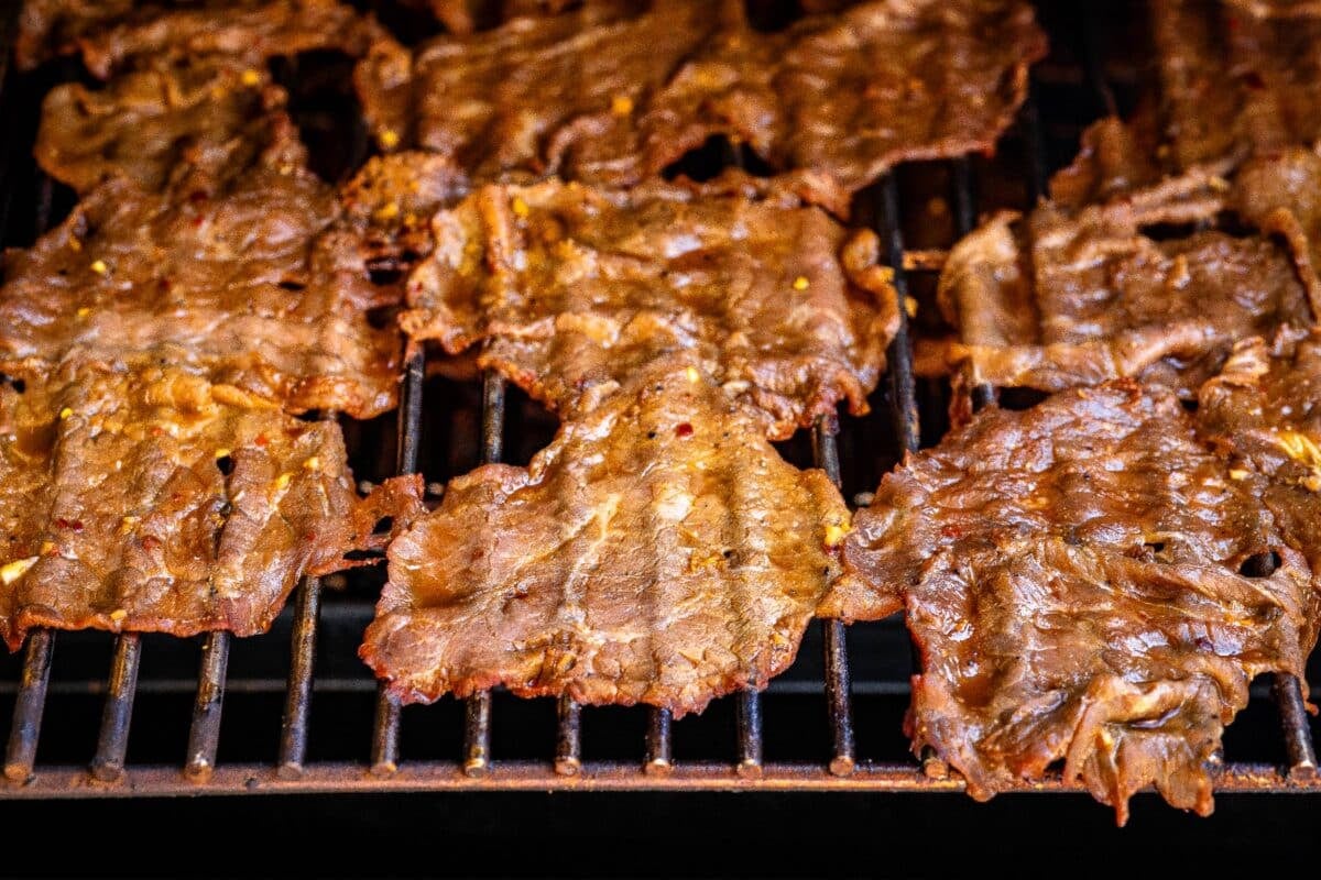 Jerky slices on the grates of a smoker.