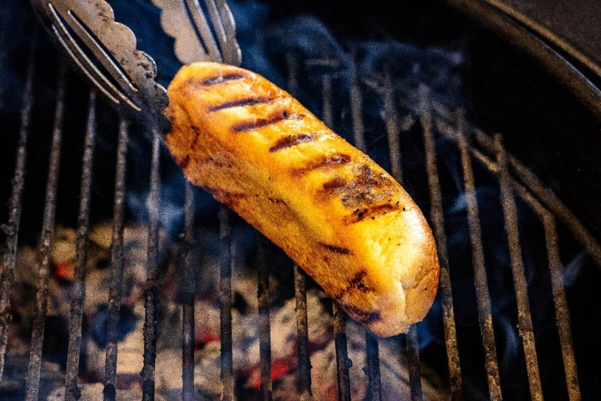 A bun toasting on grates over charcoal.