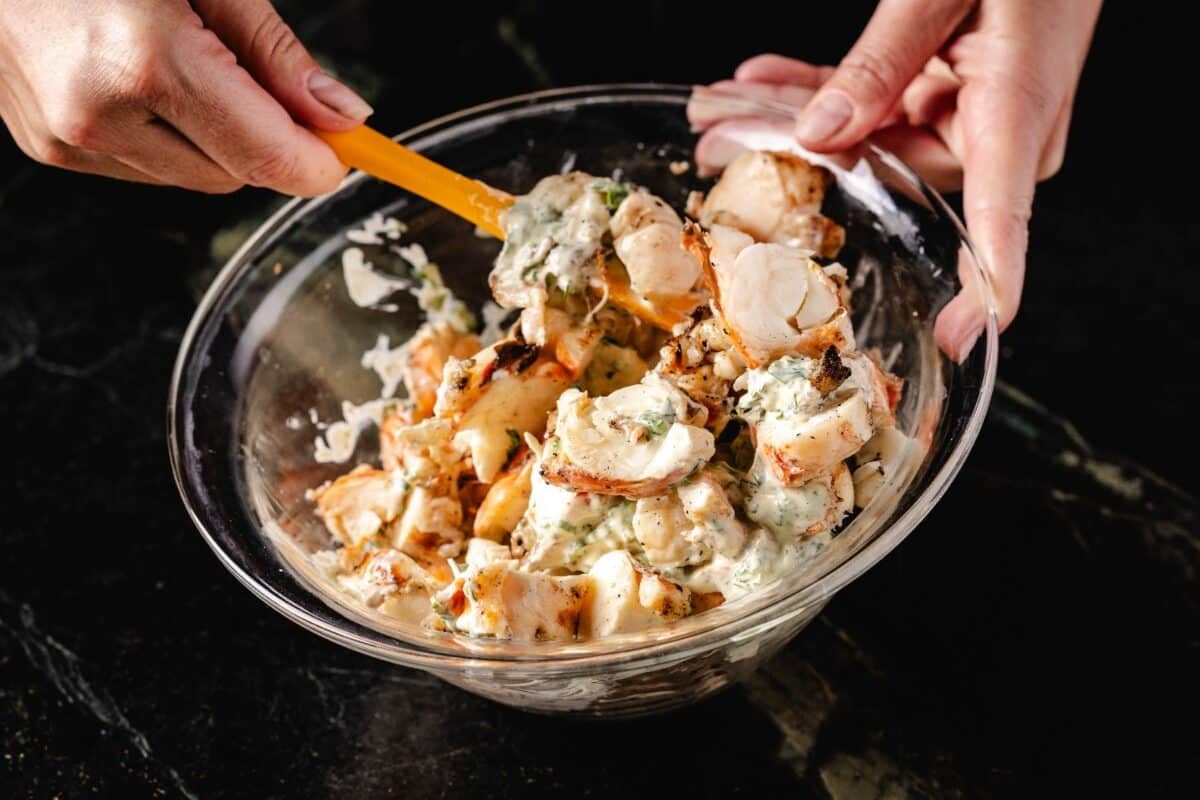 Dressing in a glass bowl being mixed with a wooden spoon.