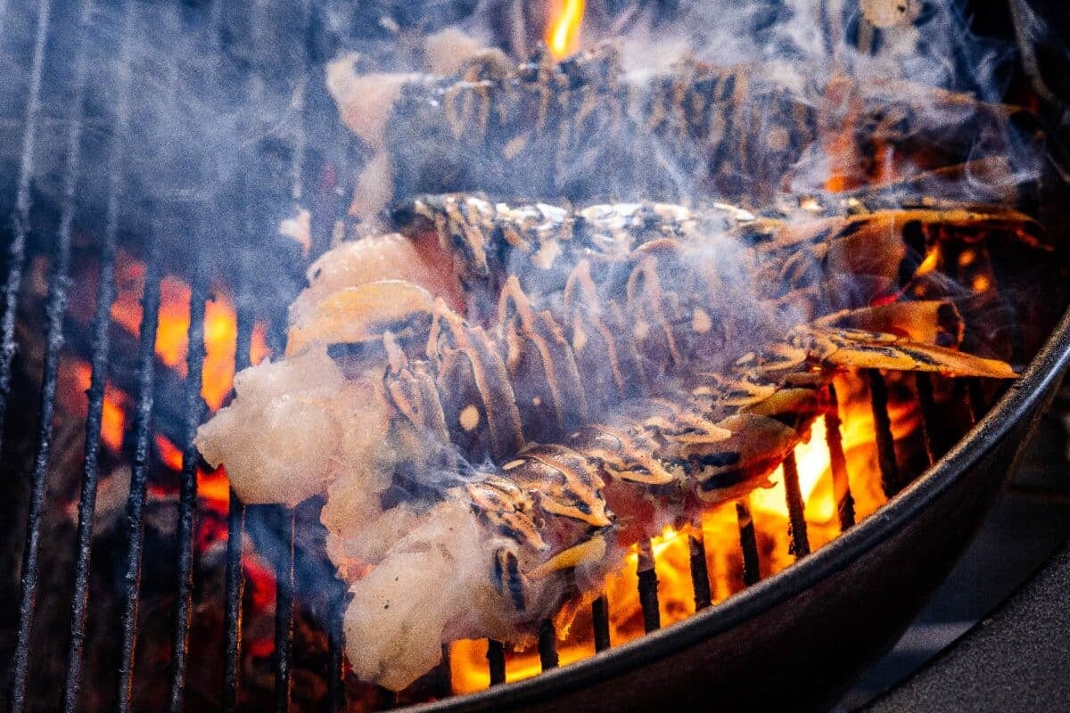 Shellfish sitting on grill grates over flames.