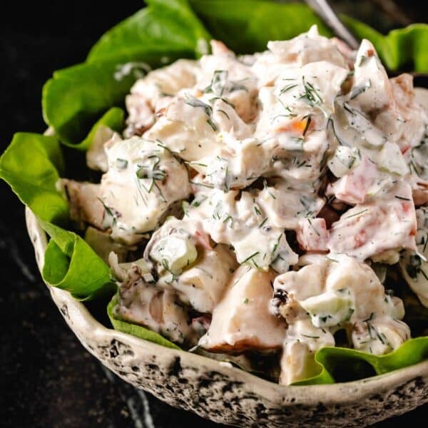 Lobster salad in a white bowl garnished with leaves of butter lettuce.