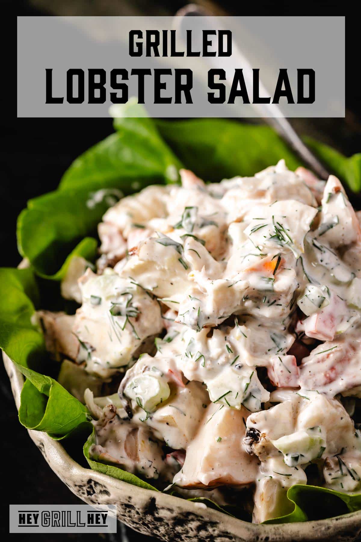 Lobster salad in a white bowl garnished with leaves of butter lettuce. The text overlay reads "Grilled Lobster Salad" at the top, and "Hey Grill Hey" at the bottom.