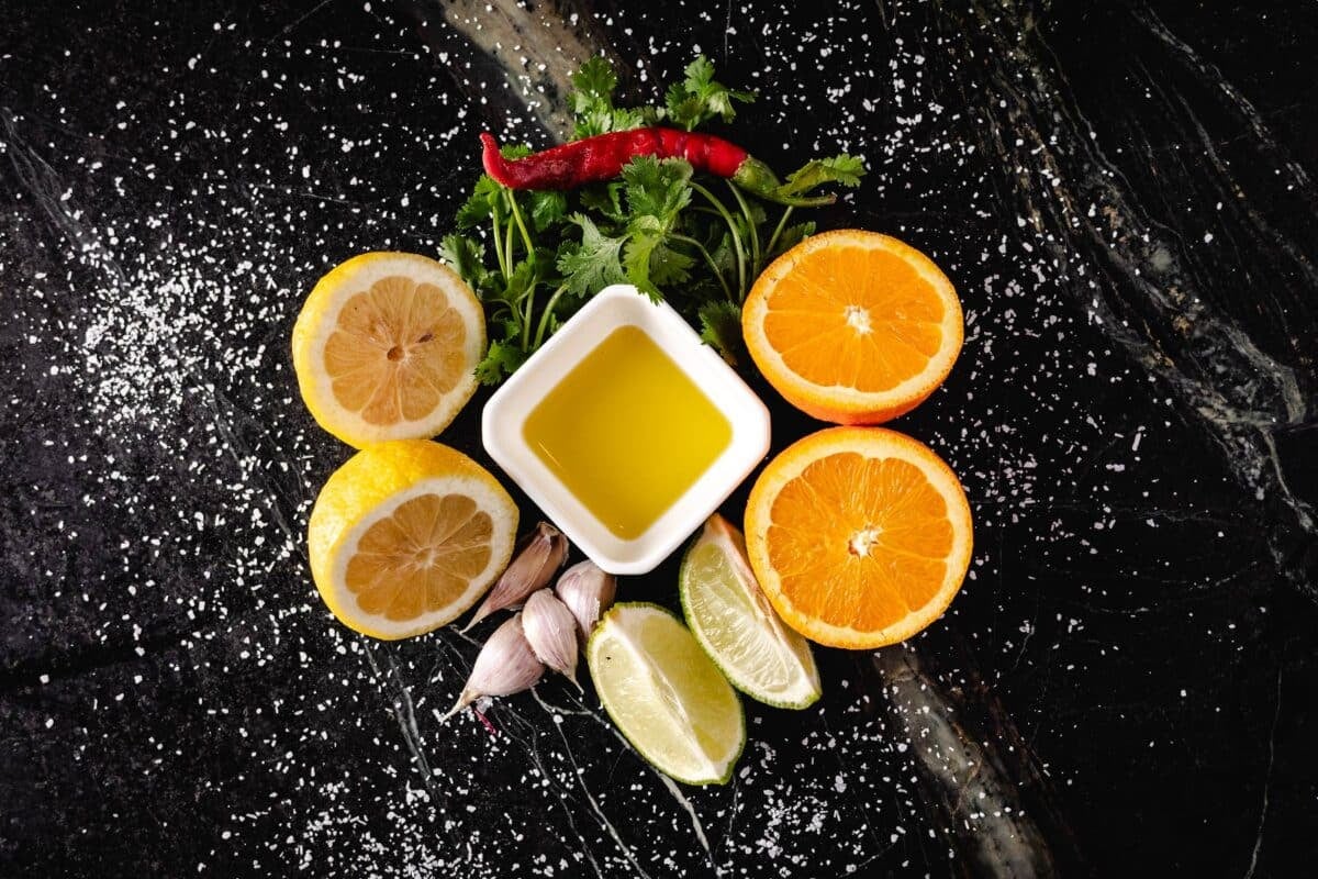 Citrus halves, garlic cloves, and a bowl of oil on a countertop.