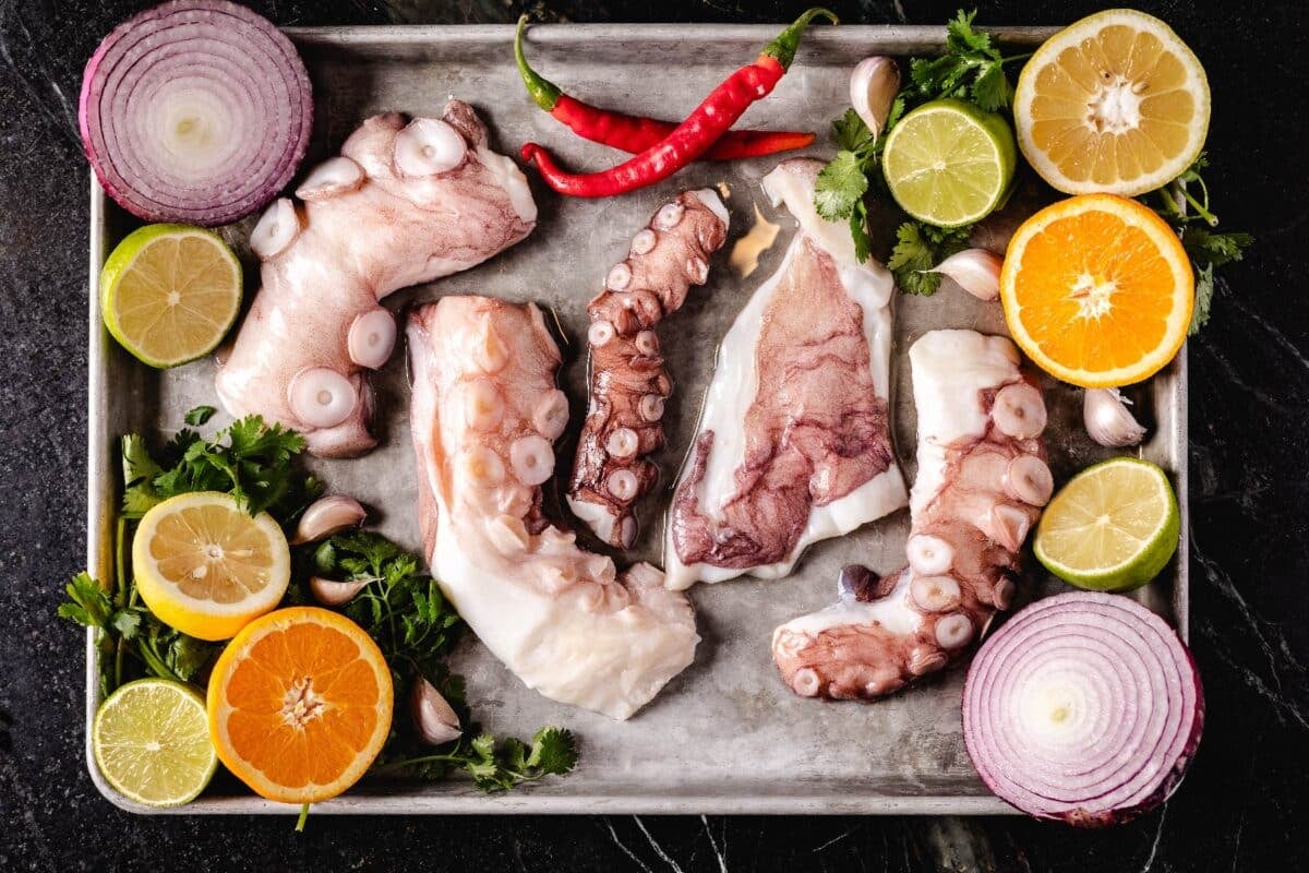 Peppers, citrus halves, onion halves, and squid tentacles on a baking sheet.