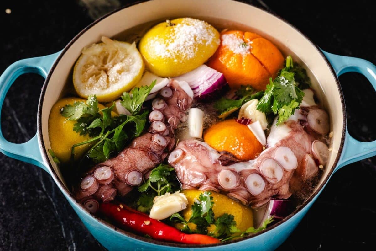 Seafood and citrus braising in a blue pot.