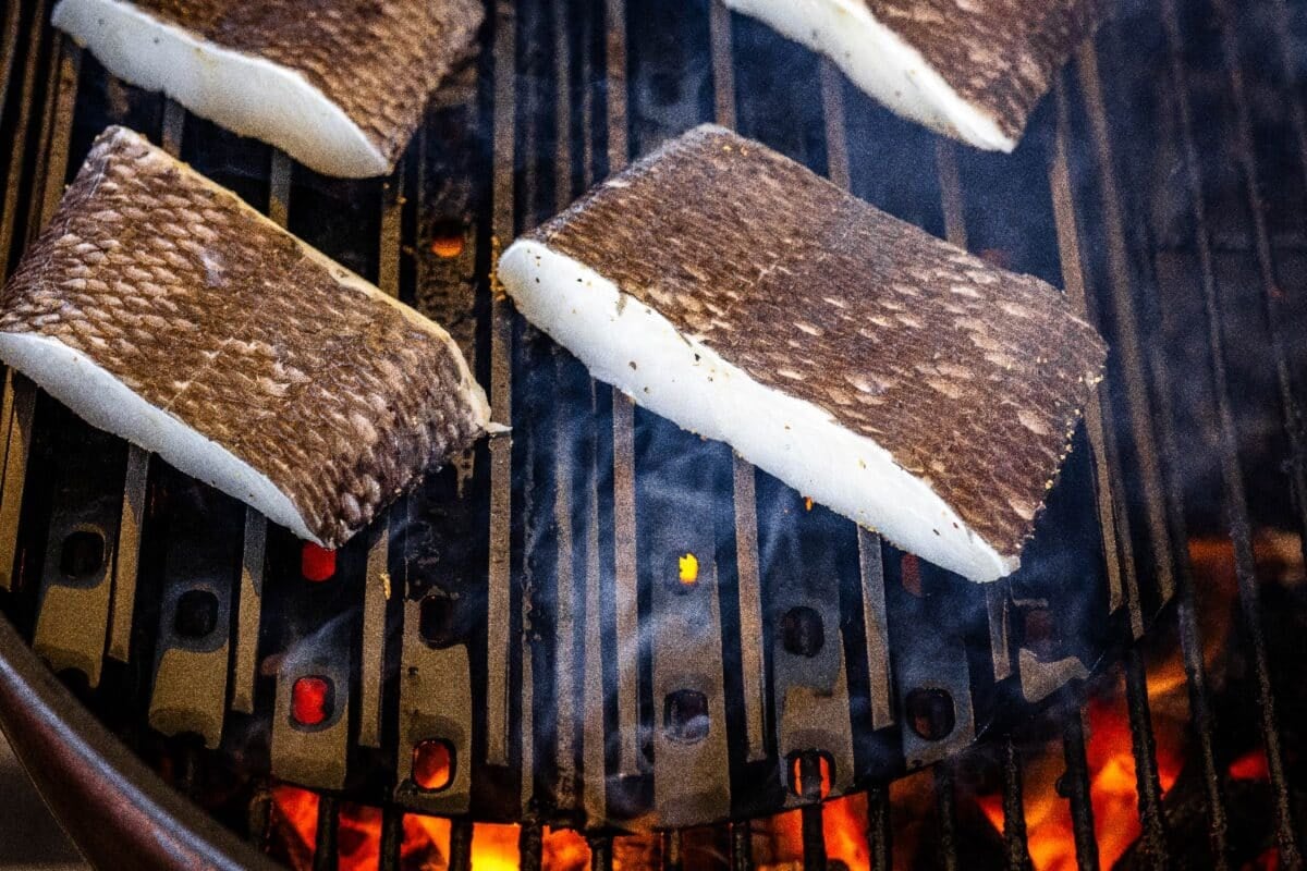 Sea bass fillets sitting on grill grates.