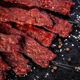 Jerky strips on a black plate sprinkled with flaky salt.