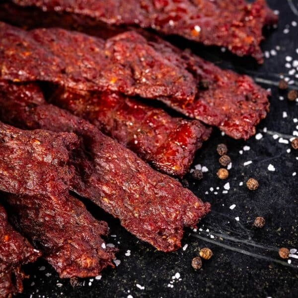 Jerky strips on a black plate sprinkled with flaky salt.